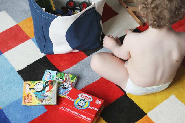 Toddler playing on The Land of Nod rug in a boys' shared bedroom
