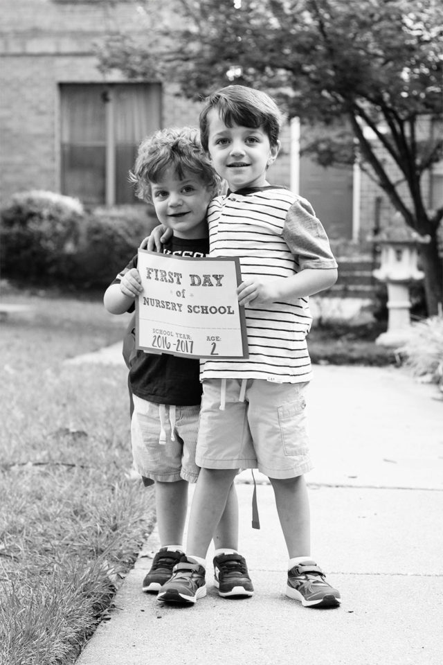 Brothers holding a first day of nursery school sign together
