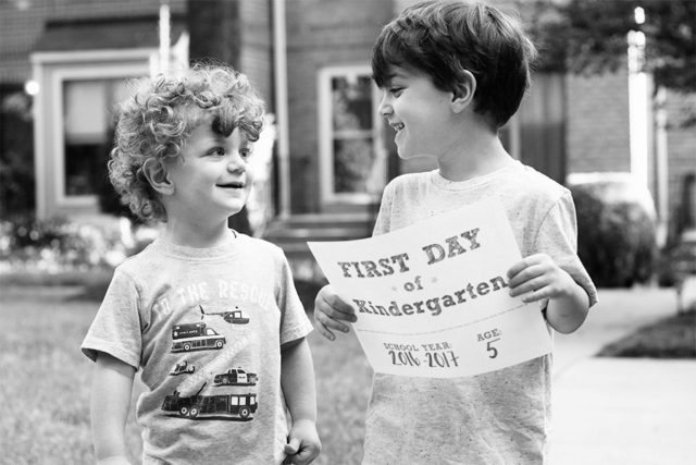 Brothers on the first day of school holding a kindergarten sign