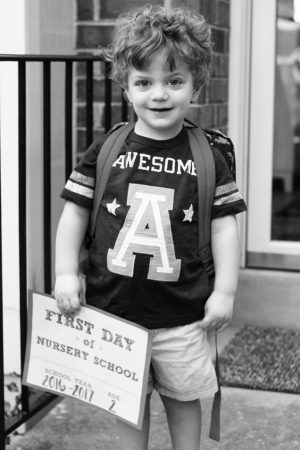 Toddler holding a first day of nursery school sign